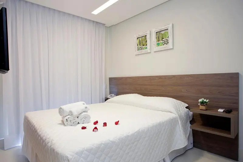 Une chambre lumineuse avec un grand lit recouvert de pétales de fleurs.