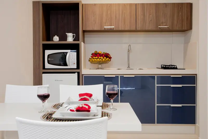 Une table est dressée devant une kitchenette équipée.