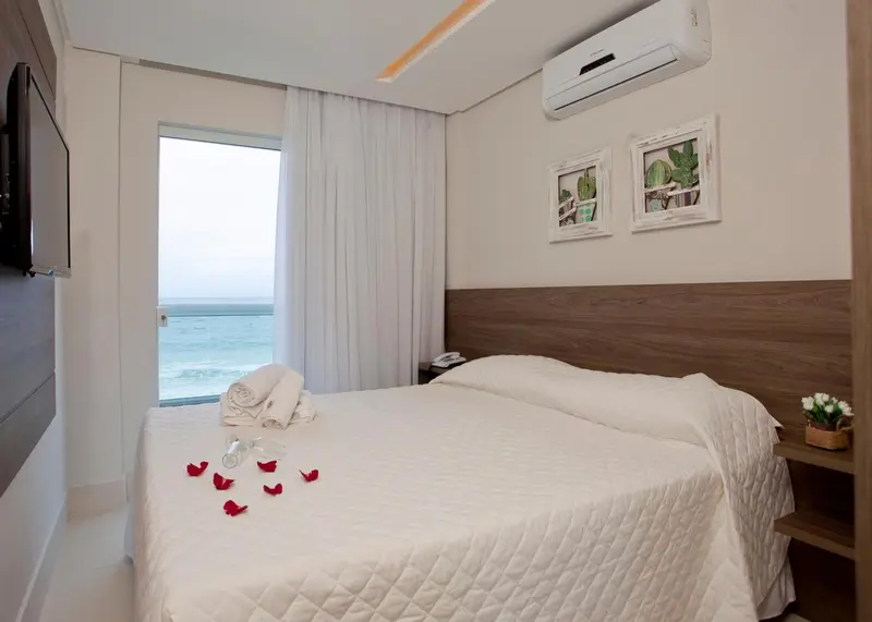 Une chambre lumineuse avec un lit fait et vue sur la mer.
