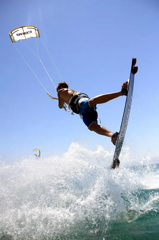 Un homme pratique le kitesurf au-dessus des vagues.