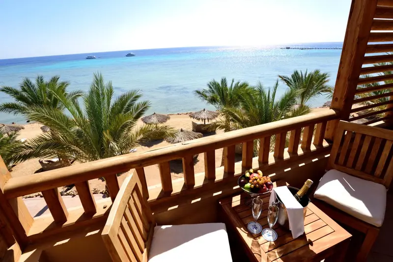 Une vue sur la mer depuis un balcon avec une table garnie de fruits et de boissons.