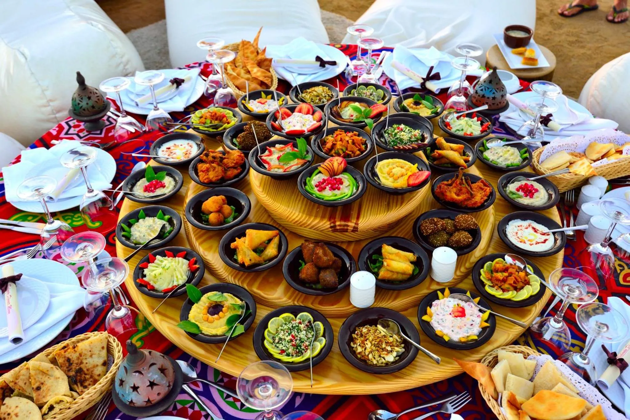 Une table basse est garnie de nombreux petits plats colorés et de pains.