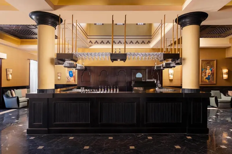 Un comptoir de bar en bois sombre se dresse dans un hall spacieux et élégant.