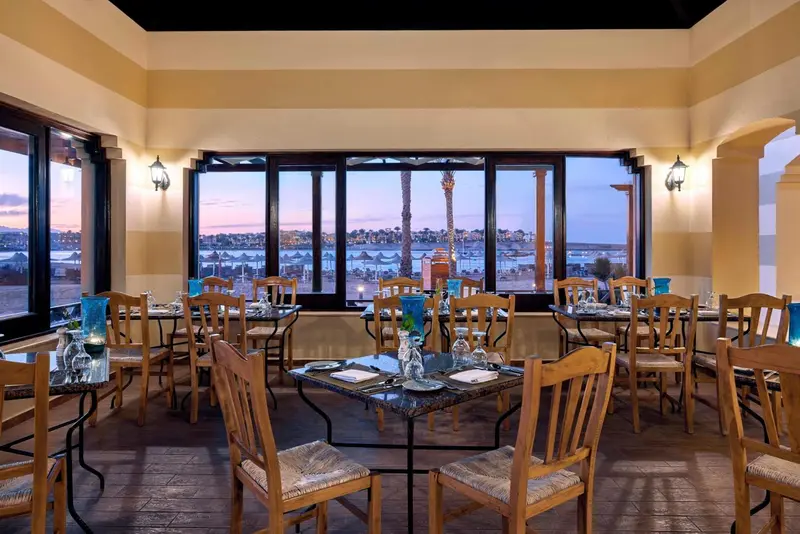 Une salle de restaurant lumineuse avec vue sur la mer au coucher du soleil.