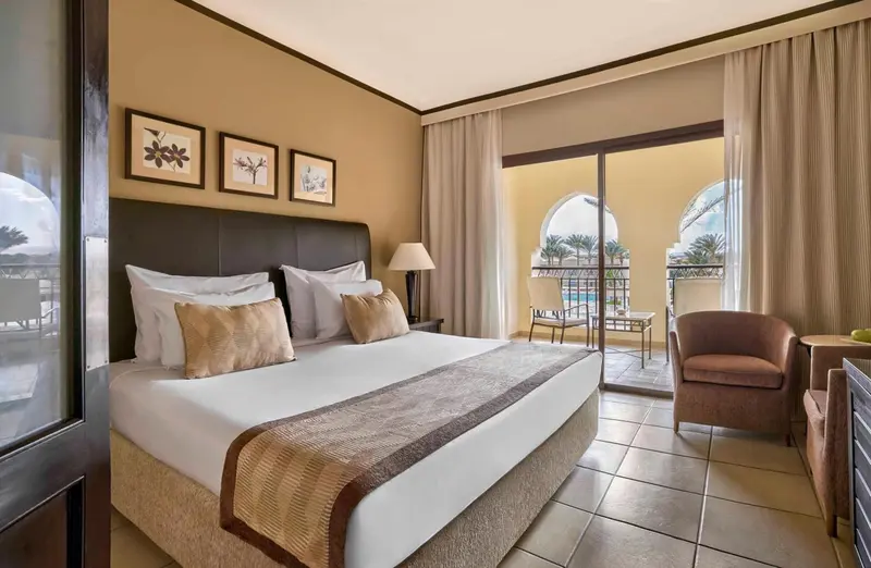 Une chambre lumineuse avec un grand lit et un accès à un balcon.