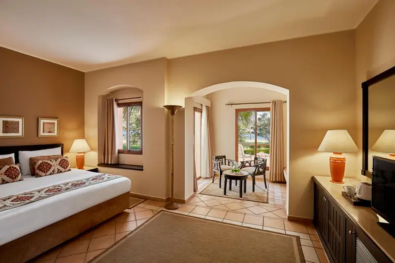 Une chambre lumineuse avec un lit double et un espace salon attenant.