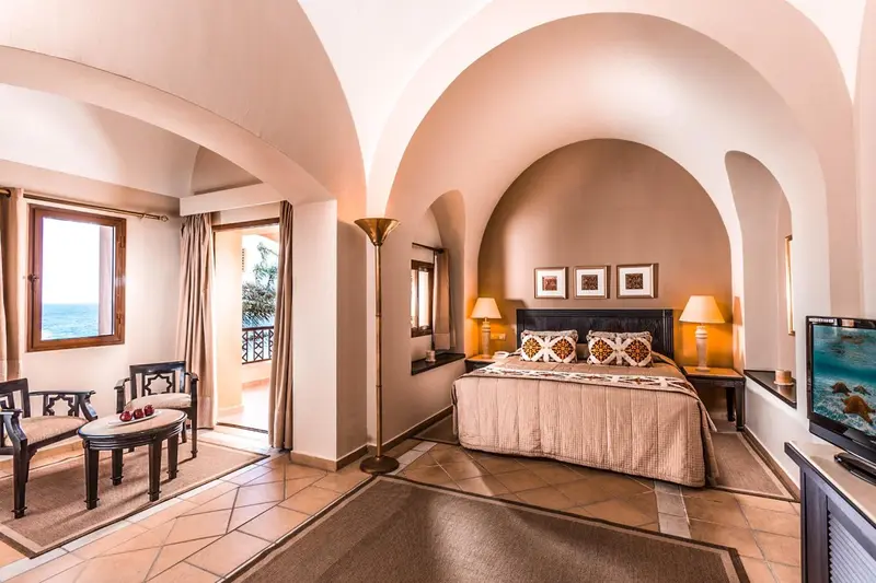 Une chambre lumineuse avec un lit double et un coin salon donnant sur une vue mer.
