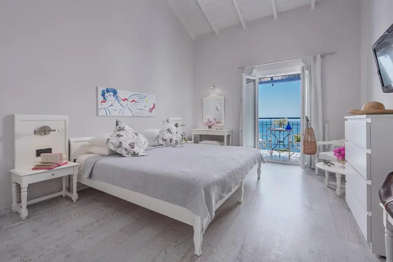 Une chambre lumineuse avec un lit blanc et un accès à un balcon.