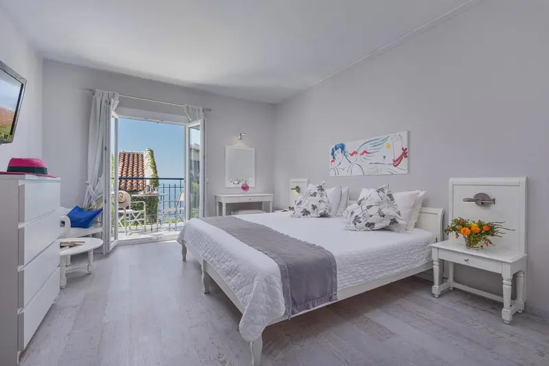 Chambre lumineuse avec un lit double et un accès à un balcon.