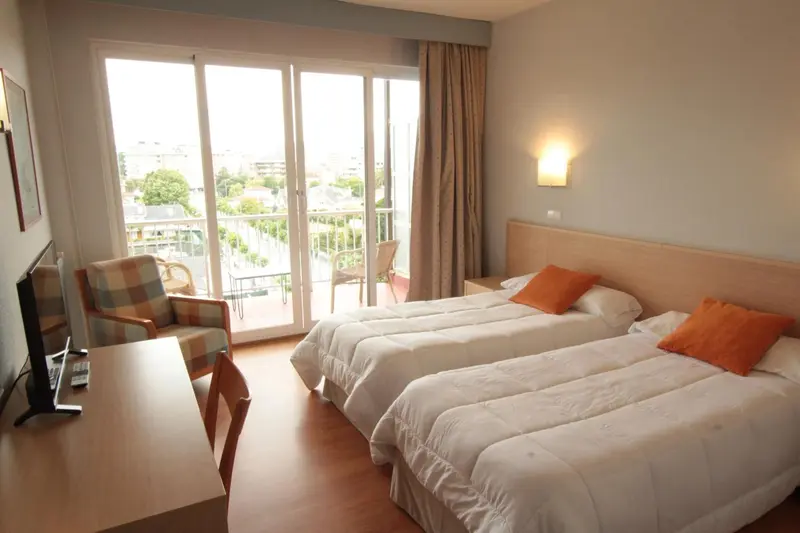 Une chambre lumineuse avec deux lits et un accès à un balcon.