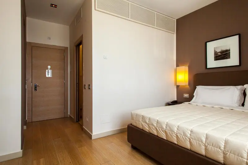 Une chambre lumineuse avec un lit fait et un parquet clair.