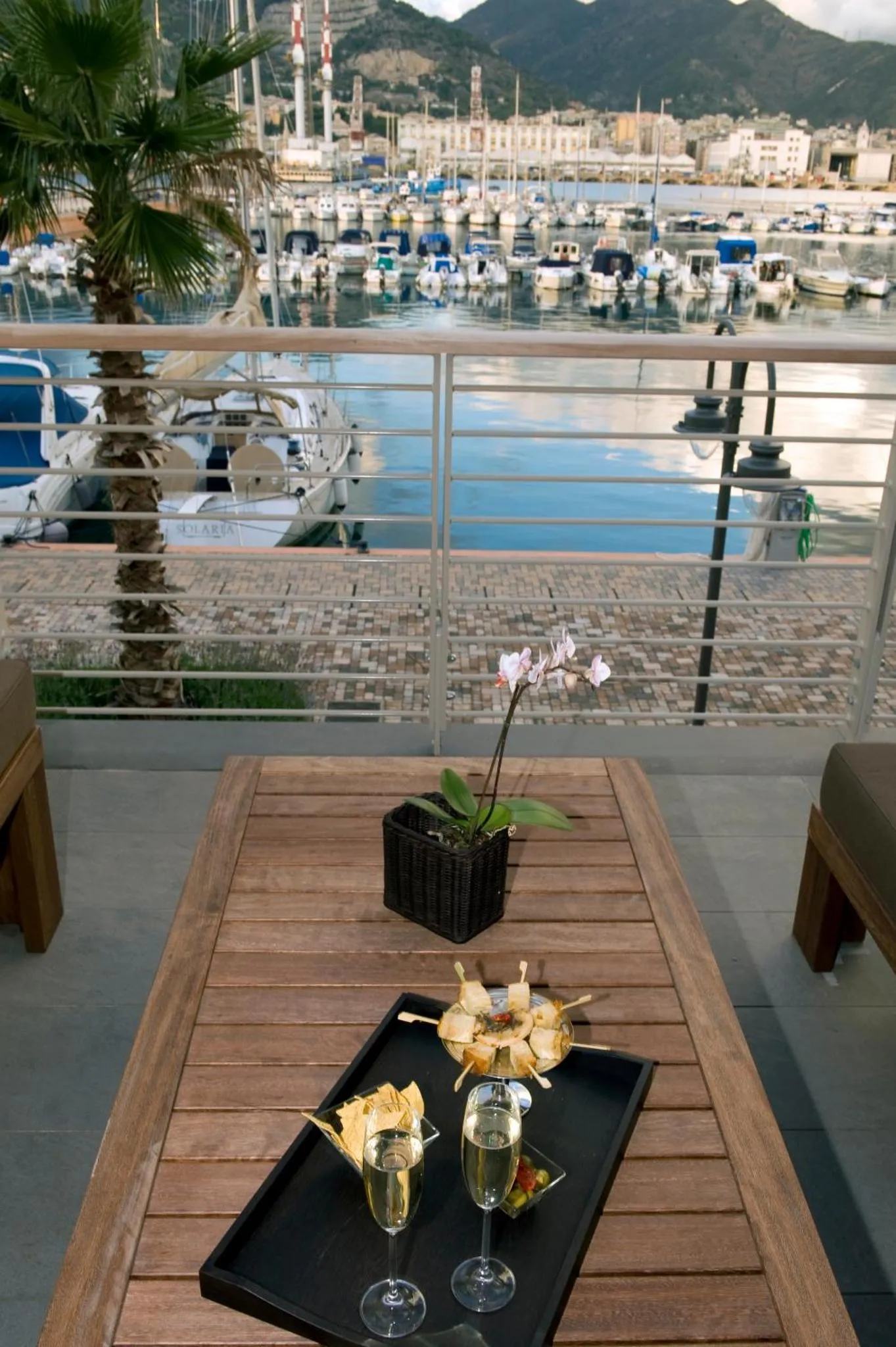 Une table en bois avec des boissons et des fleurs sur une terrasse ensoleillée.