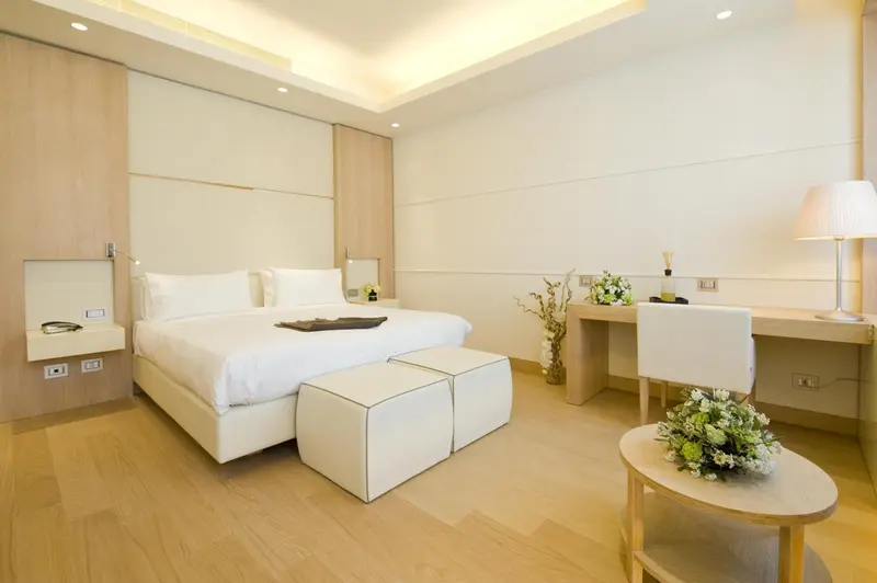 Chambre lumineuse avec un grand lit et un espace bureau.