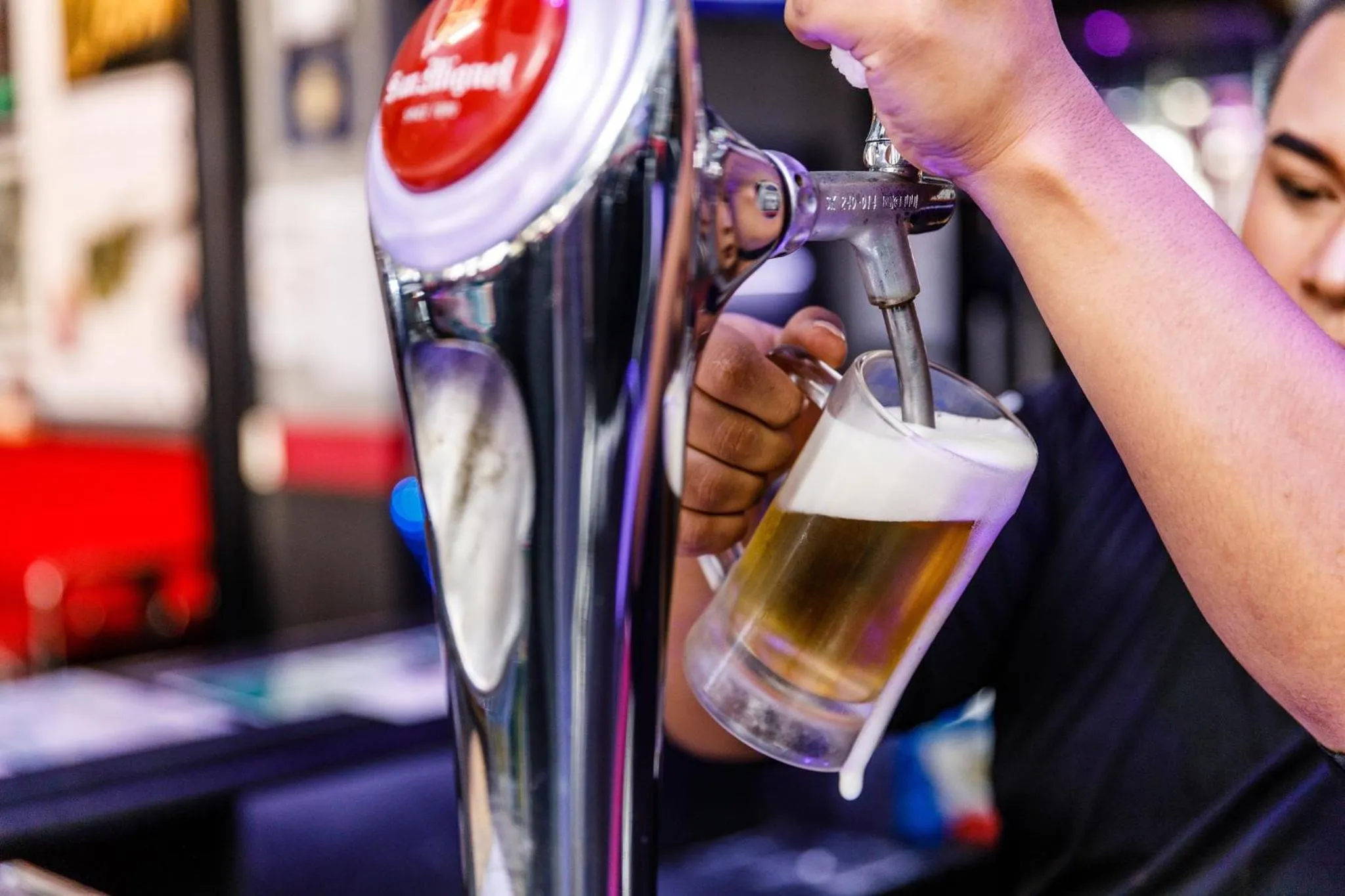 Une main verse de la bière mousseuse dans un verre.