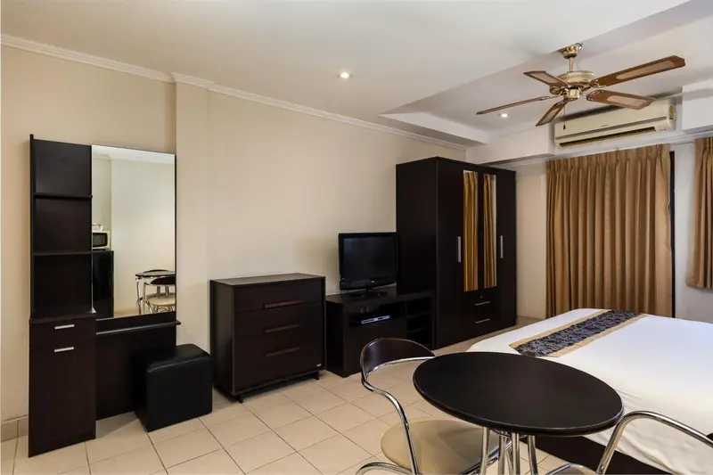 Une chambre d'hôtel avec un lit, un meuble de rangement et une petite table.
