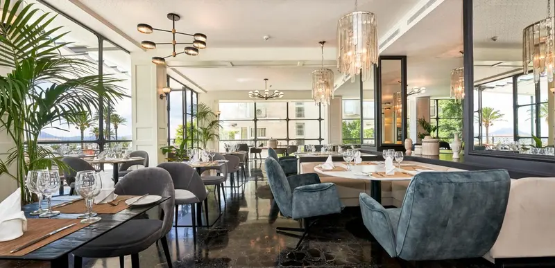 Une salle lumineuse avec des tables dressées pour un repas.