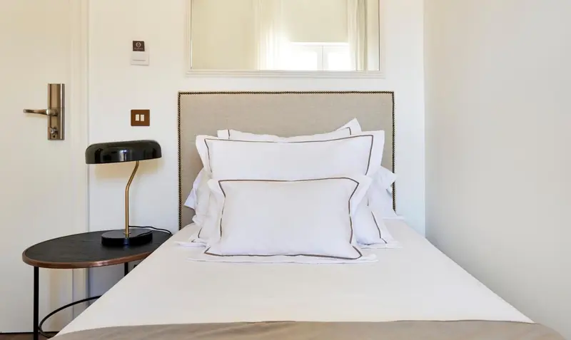 Un lit avec des oreillers blancs et une lampe de chevet sur une table de nuit.