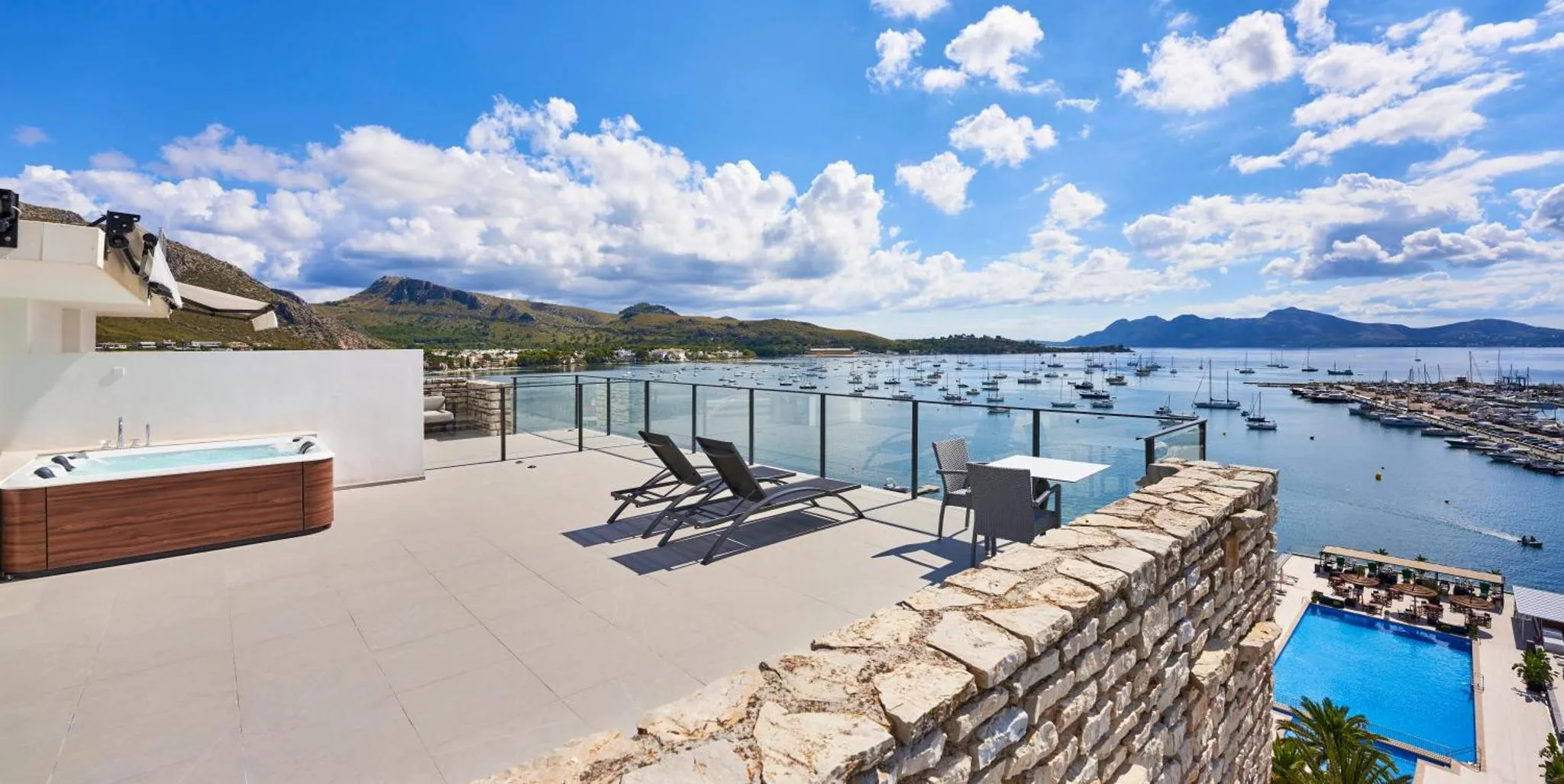 Terrasse aménagée avec jacuzzi, chaises longues et table face à la mer.