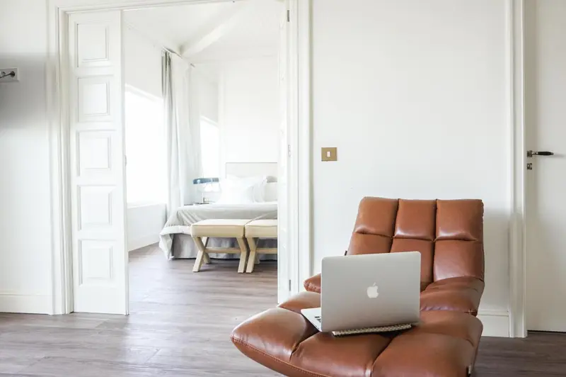 Une chaise en cuir marron et un ordinateur portable sont posés dans une pièce lumineuse.