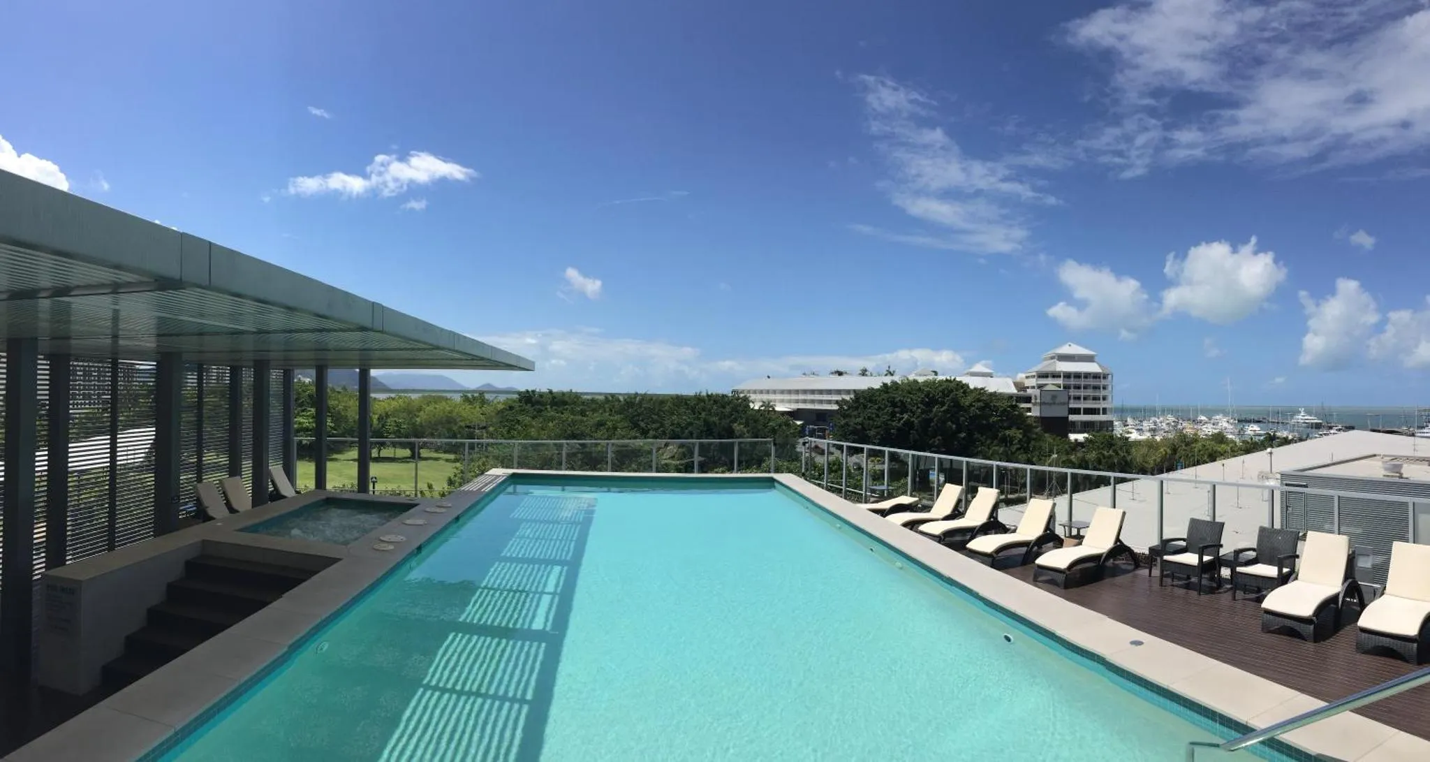 Piscine sur toit-terrasse avec transats et vue sur la ville.