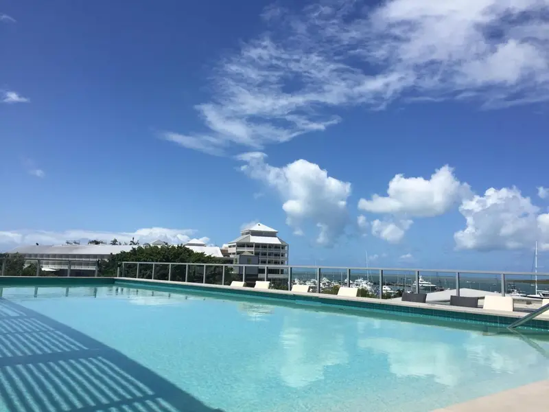 Piscine bleue avec vue sur la mer et un bâtiment blanc.
