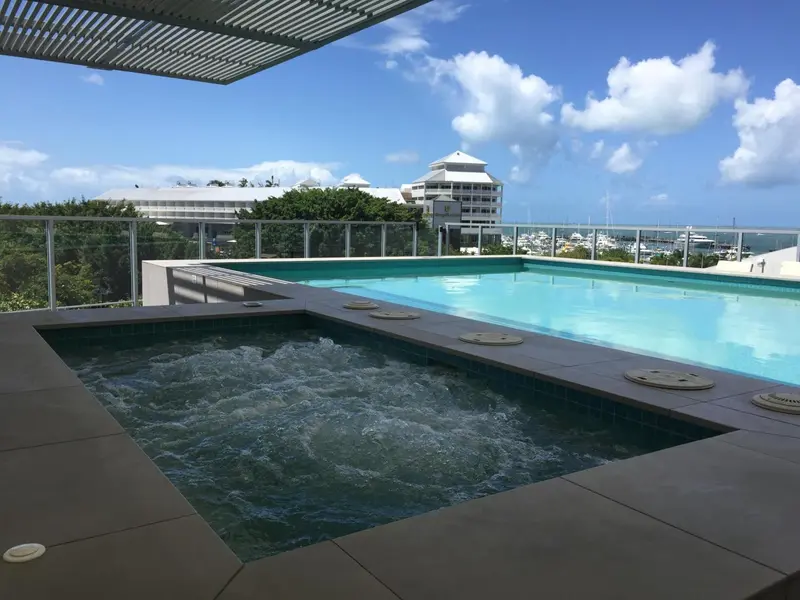 Piscine avec jacuzzi et vue sur la mer et les bâtiments environnants.