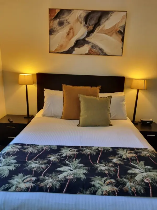 Une chambre avec un grand lit recouvert d'une courtepointe à motifs et de coussins décoratifs.