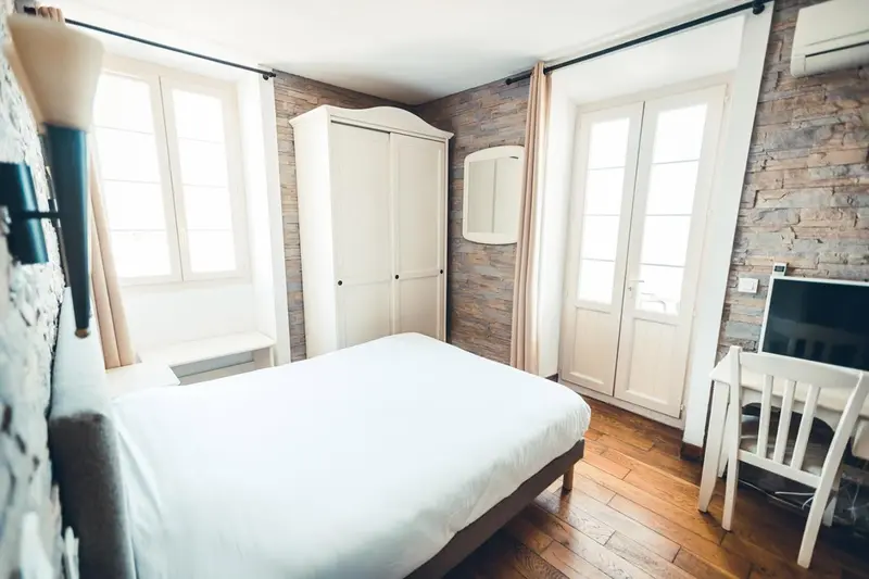 Une chambre lumineuse avec un lit blanc et un bureau en bois.