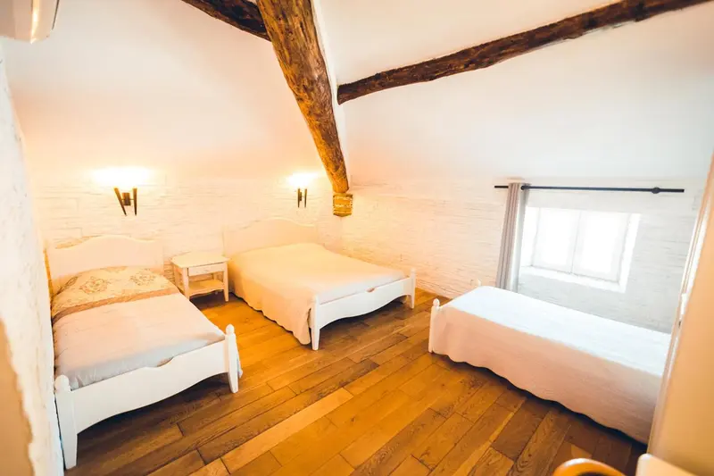 Une chambre lumineuse avec deux lits simples et un lit individuel.