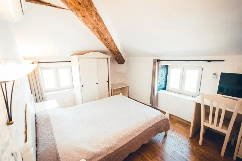 Une chambre lumineuse avec un lit recouvert d'une courtepointe et un bureau en bois.