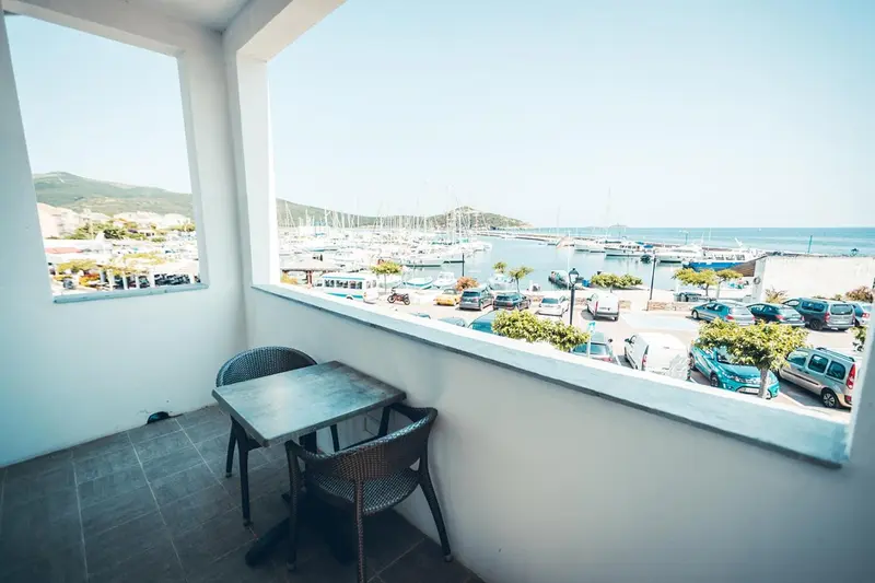Une table et des chaises en osier sont disposées sur une terrasse avec vue sur un port de plaisance.