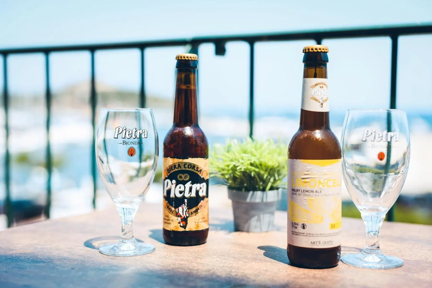 Deux bouteilles de bière et deux verres sur une table en extérieur avec vue sur la mer.