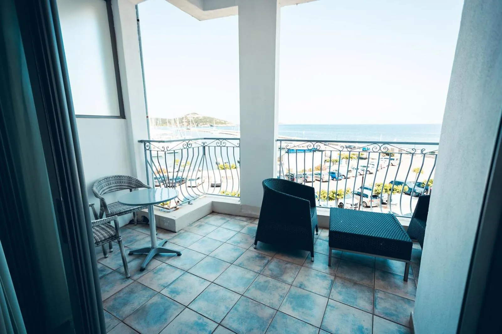 Une terrasse avec mobilier d'extérieur offre une vue sur la mer et la promenade.