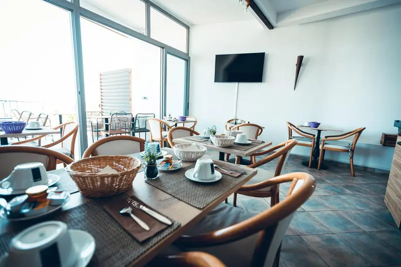 Une table est mise avec des couverts et des viennoiseries dans une salle lumineuse.