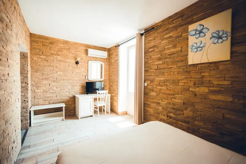 Une chambre lumineuse avec un mur en pierre et un bureau blanc.