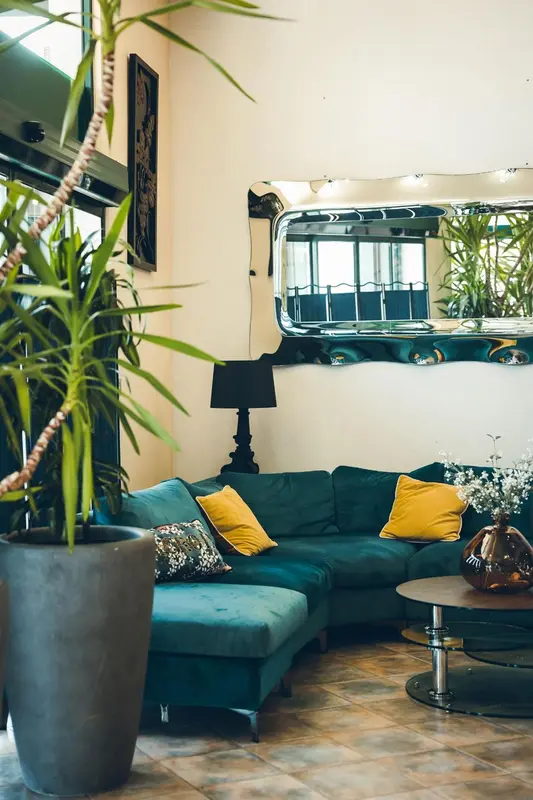 Un canapé vert et des coussins colorés dans un espace de détente intérieur.