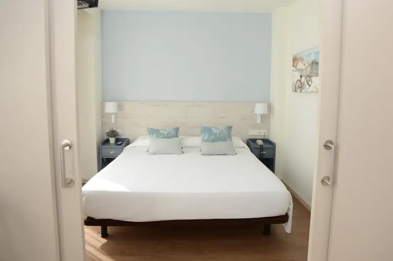 Une chambre lumineuse avec un grand lit recouvert de draps blancs et de coussins.
