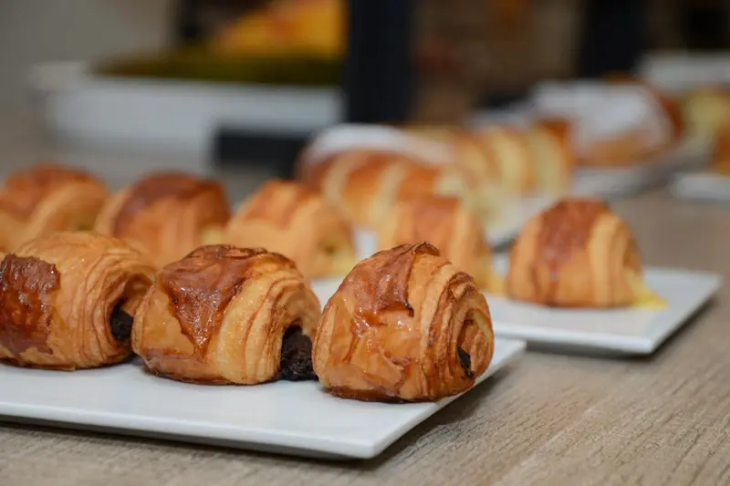 Présentation de viennoiseries dorées sur un plateau blanc.