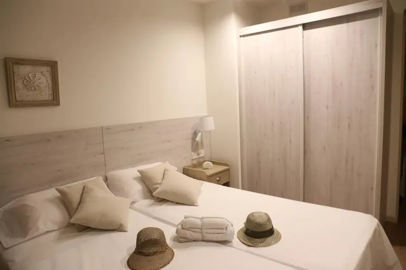 Une chambre lumineuse avec un grand lit recouvert d'oreillers et de coussins.