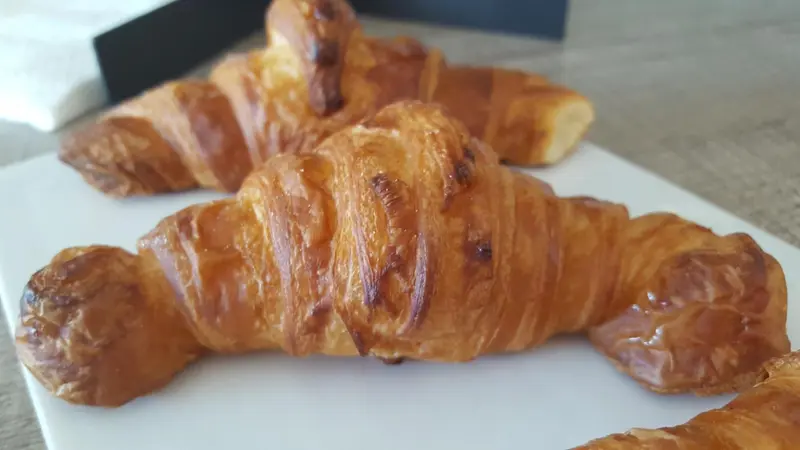 Des viennoiseries dorées sont présentées sur une assiette blanche.