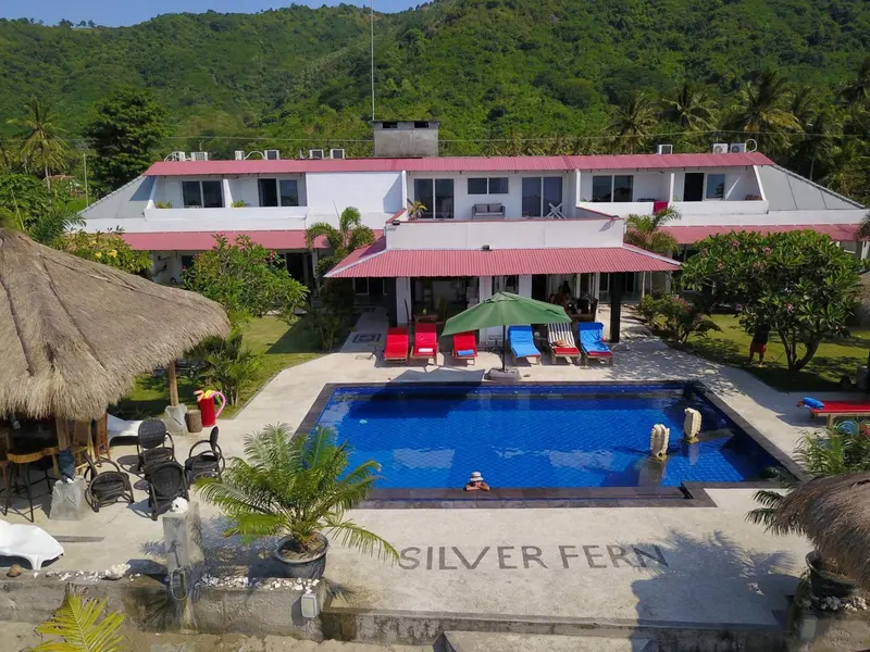 Vue aérienne d'un bâtiment blanc avec une piscine et des transats.