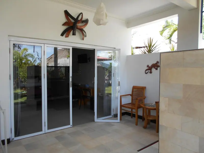 Espace extérieur avec mobilier et accès à un intérieur lumineux.