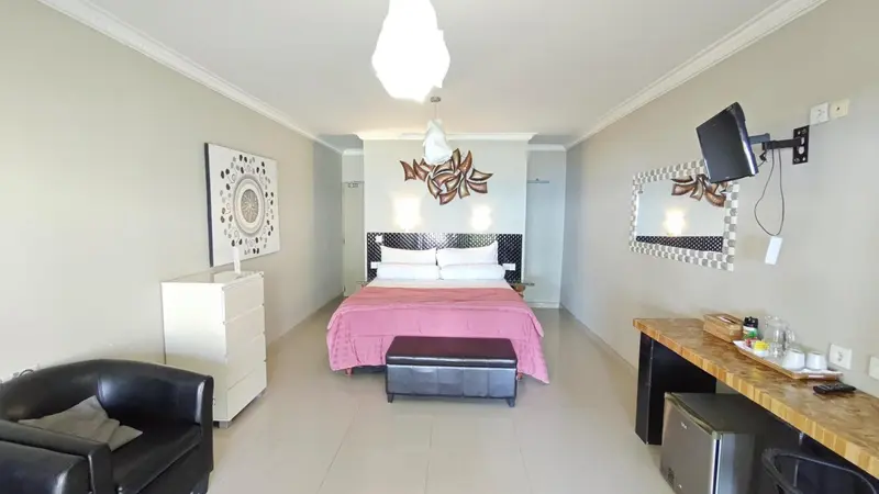 Une chambre lumineuse avec un grand lit et un téléviseur mural.
