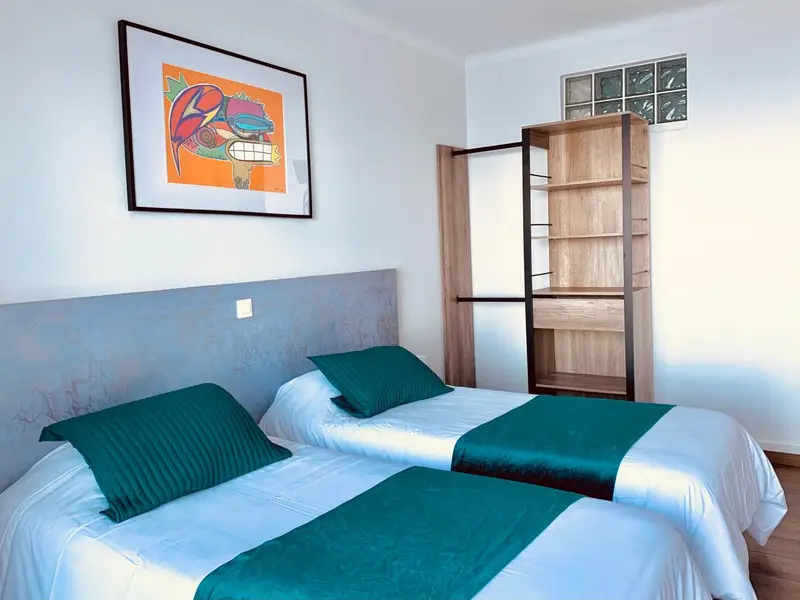 Une chambre avec deux lits simples et une décoration murale colorée.