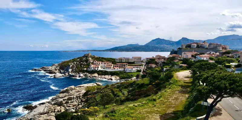 Vue panoramique sur une côte rocheuse et un village en bord de mer.