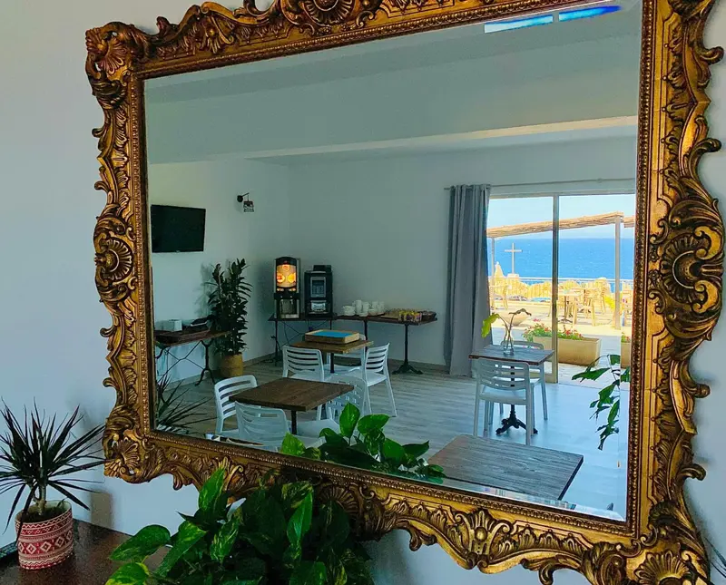 Une pièce lumineuse avec un miroir doré et une vue sur la mer.