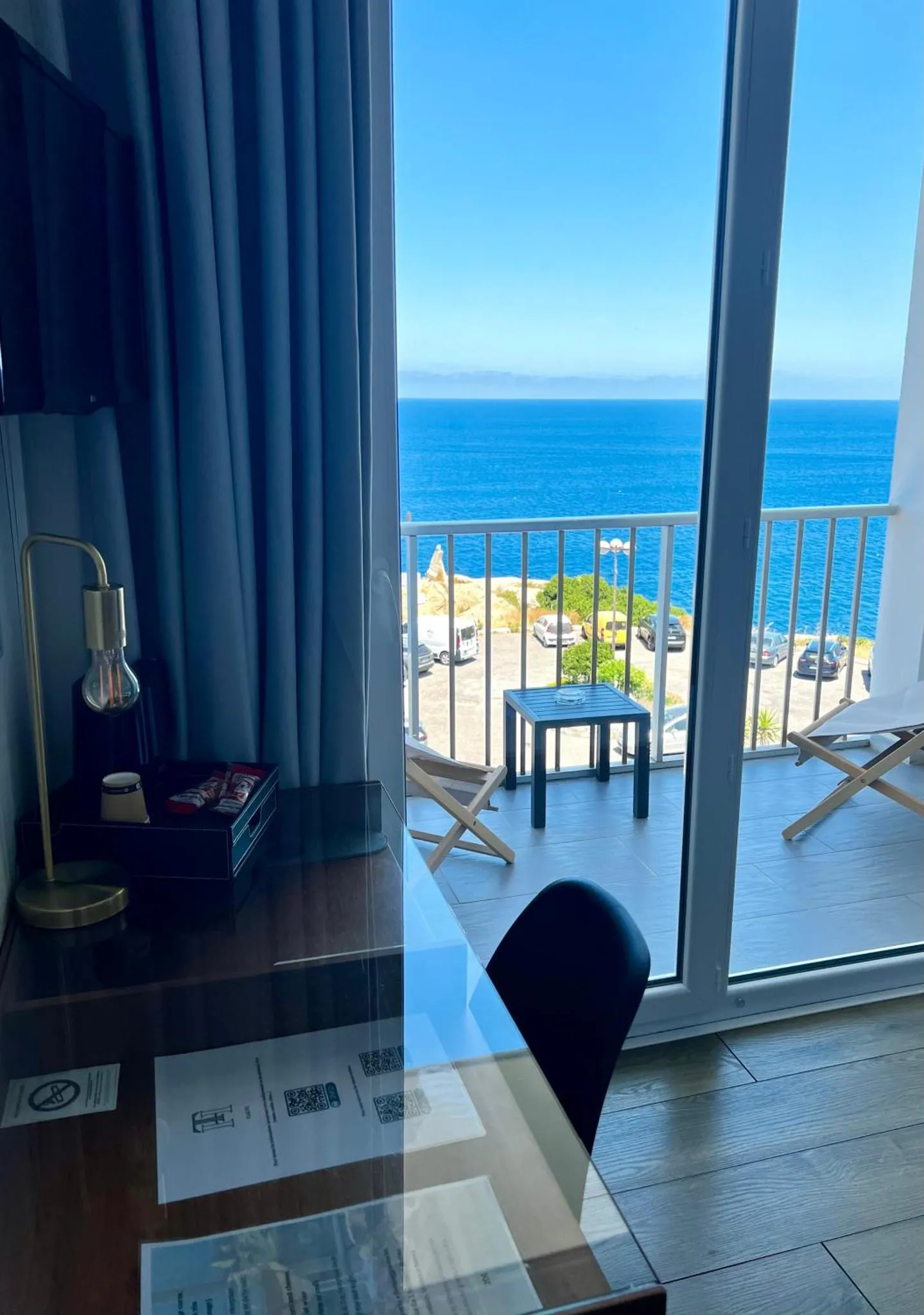 Vue sur la mer depuis une chambre avec un bureau et une terrasse.