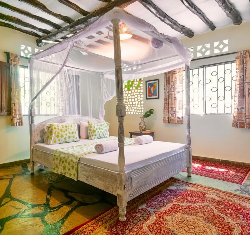 Lit à baldaquin dans une chambre décorée de motifs floraux et de couleurs vives.