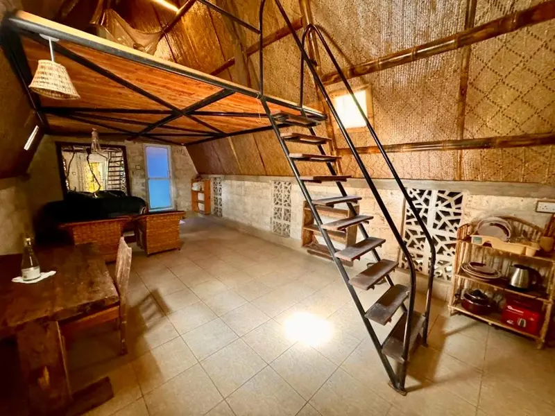 Une pièce spacieuse avec un escalier en métal menant à une mezzanine.