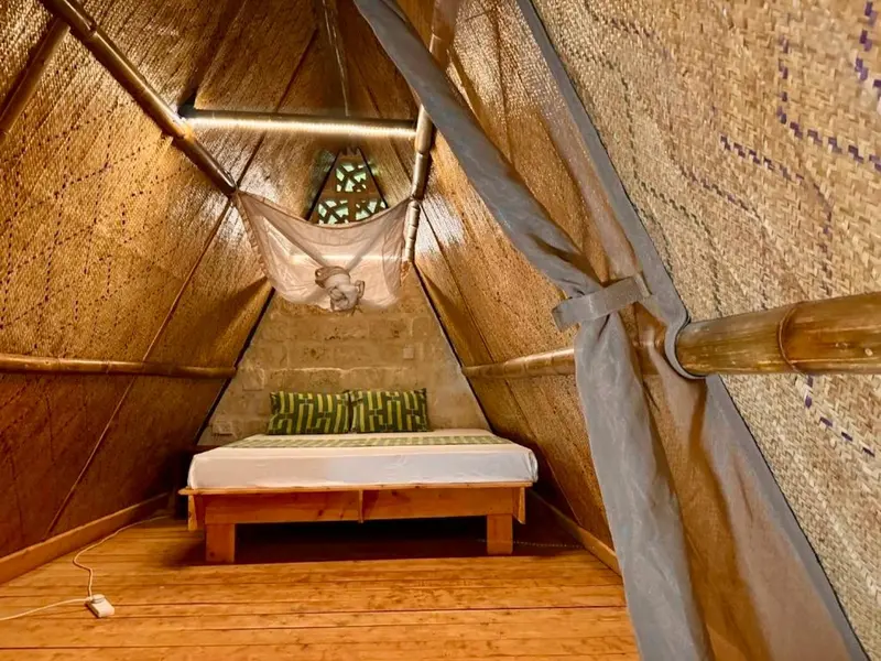 Une chambre mansardée en bois avec un lit recouvert d'un moustiquaire.